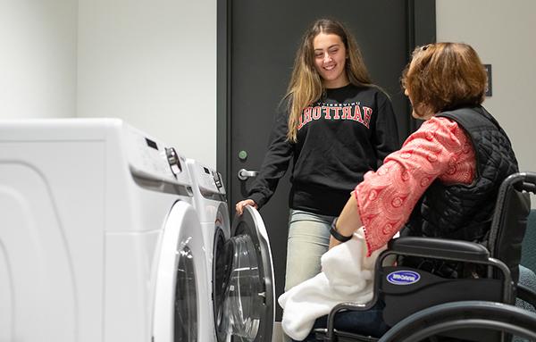 student helping client with laundry